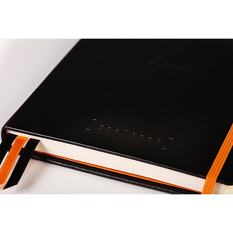 Carnet noir avec signet orange. 'Notebook' est gaufré sur la couverture.