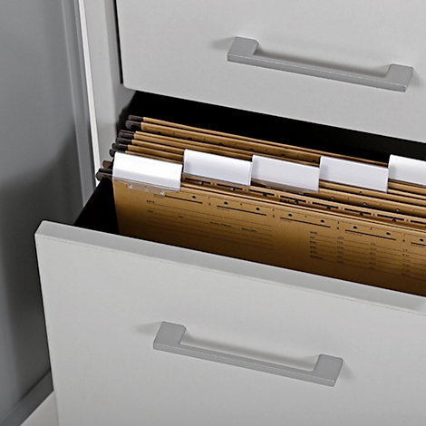 Open drawer of a white filing cabinet filled with brown documents and white tabs.