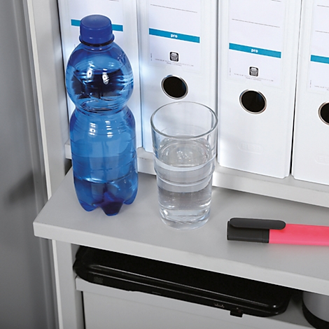 Blauwe waterfles en glas water naast ordners op een plank.
