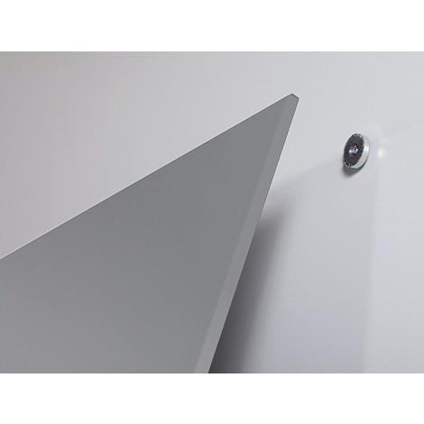 Graue, dreieckige Form vor weißer Wand. Rechts davon ein kleiner, runder Magnet.