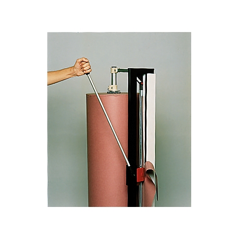 A hand operates a paper cutter. The cutter slices paper from a large roll.