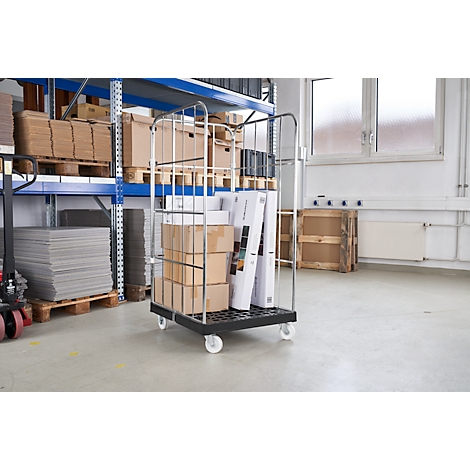 Wagentje met dozen en documenten in magazijn. Rekken met goederen op de achtergrond.