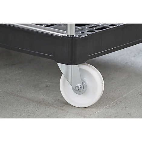 Detailopname van een wit zwenkwiel op een zwarte winkelwagen, staand op een grijze vloer.