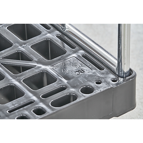 Detailopname van een zwarte kunststof plank met gaten en een metalen paal.