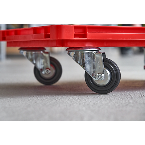 Close-up of two wheels under a red plastic container. The wheels are black with silver mounts.