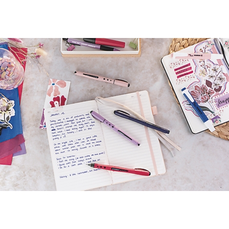 Gros plan sur des stylos et des cahiers. Cahier ouvert avec des notes manuscrites, des stylos colorés et des éléments décoratifs.