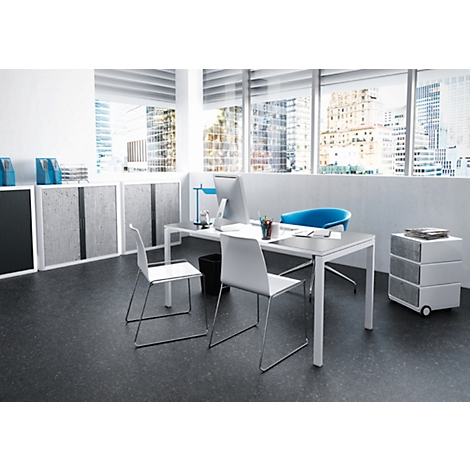 A modern office with a desk, chairs, and a view of a city. Windows with blinds, blue chair, grey cabinets and dark floor.