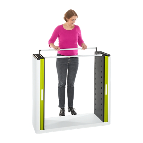 Woman in pink shirt stands at a white trade show stand with green and black accents and holding bars.