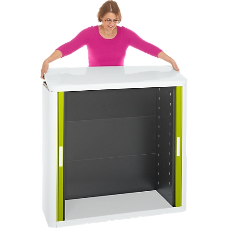 Woman with glasses opening a white cabinet with greenish elements.