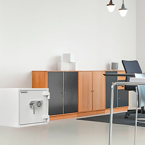 Coffre-fort blanc dans un bureau, devant des armoires et un bureau.
