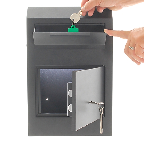 Coffre-fort noir, porte ouverte. Une personne met une clé avec un pendentif vert dans la fente.