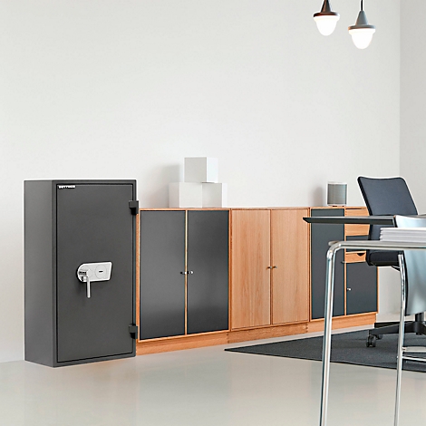 Ein dunkler Tresor steht in einem Büro mit Schrankwand, Schreibtisch und Stuhl.