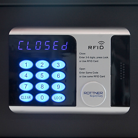 Close-up of a safe with a digital control panel. The display reads "CLOSED". Below are illuminated buttons and an RFID reader.