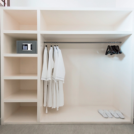 Beige inbouwkast met badjassen, hangers, kluis en slippers.
