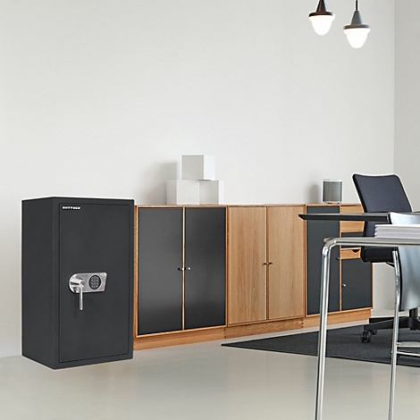 Schwarzer Tresor in einem Büro. Nebenan ein Schrank mit Schublade. Im Hintergrund weitere Schränke und ein Schreibtisch.