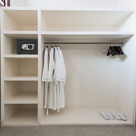 Weißer Einbauschrank mit Fächern, einer Safe, Bademäntel und Hausschuhe.