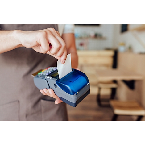 Un employé prend un reçu d'un appareil de paiement par carte bleu et gris.