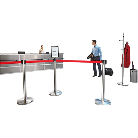 A man stands behind a red barrier. A woman stands at the counter. To the left, a coat rack with a red coat.