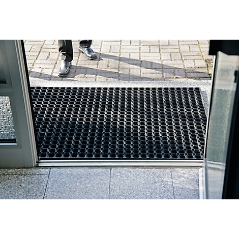 Person stands at open door, view of grid mat and paving.