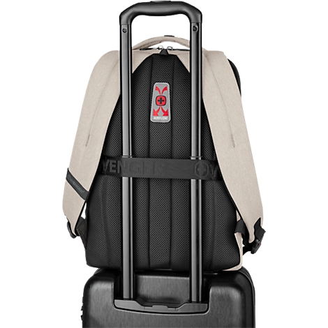 Sac à dos beige sur un chariot. Poignées noires, rembourrage dorsal et sangles. Logo rouge.