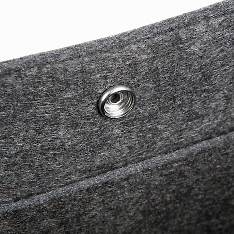 Gros plan sur une texture de feutre gris avec un bouton-pression argenté.