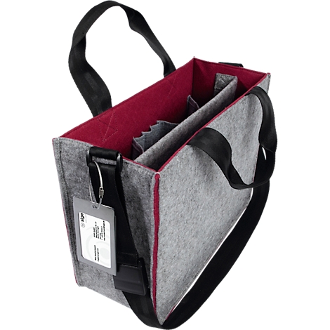 Sac en feutre gris avec des touches de rouge et des sangles de transport noires. L'intérieur est rouge, avec des compartiments. Une étiquette avec du texte est suspendue à la sangle.