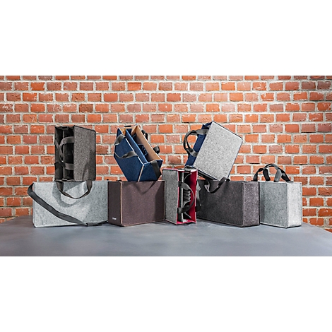 Une sélection de sacs en feutre de différentes couleurs et formes, devant un mur de briques.