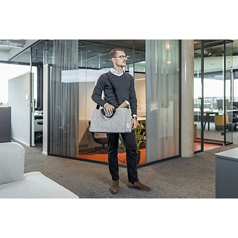 Homme avec des lunettes et un sac dans un bureau moderne, regardant sur le côté.