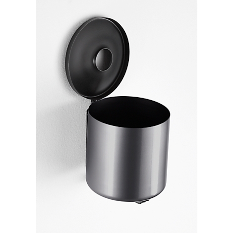 Round, black wall-mounted trash can with an open lid. The can is fixed to a white wall.