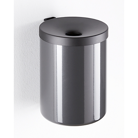 Gray, cylindrical trash can, attached to the wall. Lid with a circular opening.