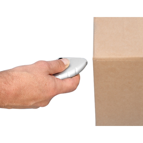 Hand holding a scanner in front of a brown box. The scanner is bright and the background is white.
