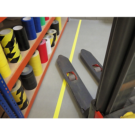 A forklift and shelves with colored adhesive tapes, yellow line on the floor.