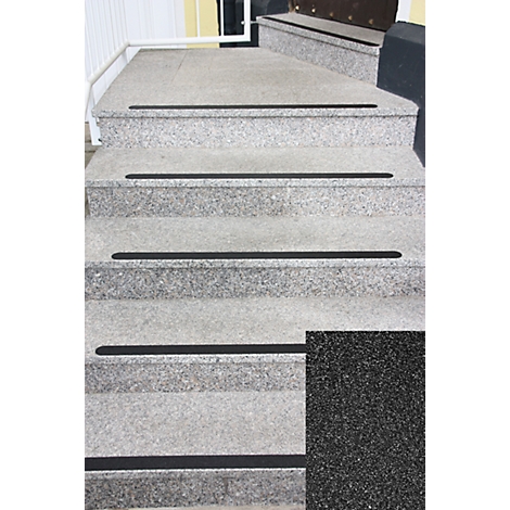 Grey stone steps with black anti-slip strips. In detail, a black, textured surface.