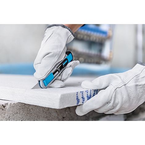 Person cutting an insulation board with a blue cutter, wearing white gloves.