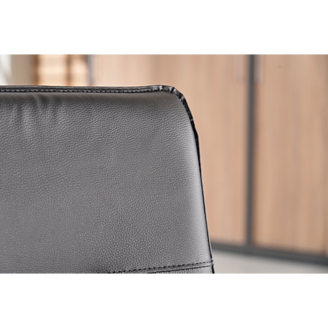 Detail of a black leather chair. The stitching is clearly visible.