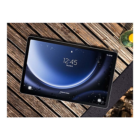 Ein Tablet mit eingeschaltetem Bildschirm liegt auf einem Holztisch. Auf dem Bildschirm sind Uhrzeit und eine blaue, geschwungene Grafik zu sehen.