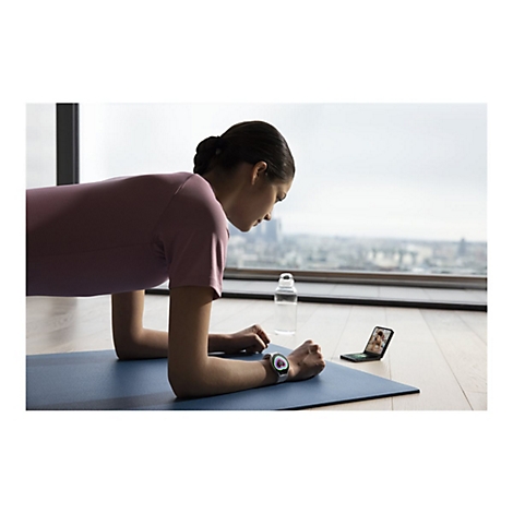 Eine Frau macht Plank-Ãœbungen. Sie trÃ¤gt eine Smartwatch und schaut auf ein Handy. Im Hintergrund ist eine Stadt zu sehen.