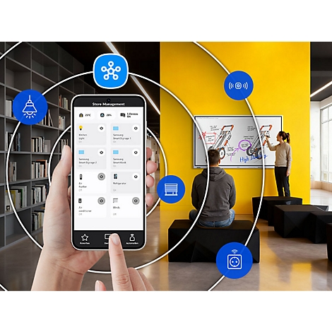 Hand hält Smartphone mit Smart-Home-App vor einem modernen Büro mit gelber Wand.
