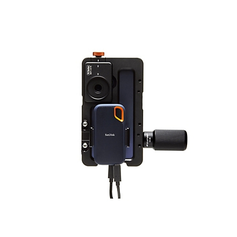 Eine Nahaufnahme zeigt eine blaue Sandisk-Festplatte, die in einem schwarzen Kameragestell mit einem Griff montiert ist. Ein Kabel ist angeschlossen.