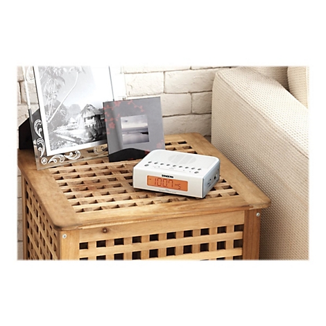 Ein weiÃŸes Digitalradio mit orangefarbener Anzeige, platziert auf einem Holztisch. Im Hintergrund: Fotos und eine Couch.