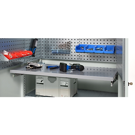 Armoire à outils avec outils et accessoires. Une perceuse et des gants sont posés sur le plan de travail. Un panneau perforé avec des outils en arrière-plan.