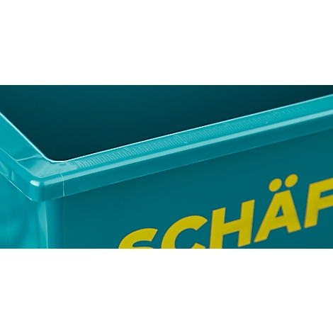 Détail d'une boîte en plastique turquoise. Le bord supérieur a un couvercle noir, avec des lettres jaunes en dessous.