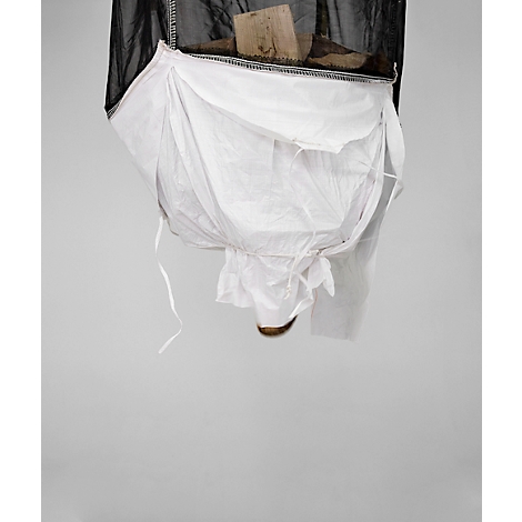 Gros plan d'un sac en tissu blanc attaché à un filet noir. Un morceau de bois est posé dessus.