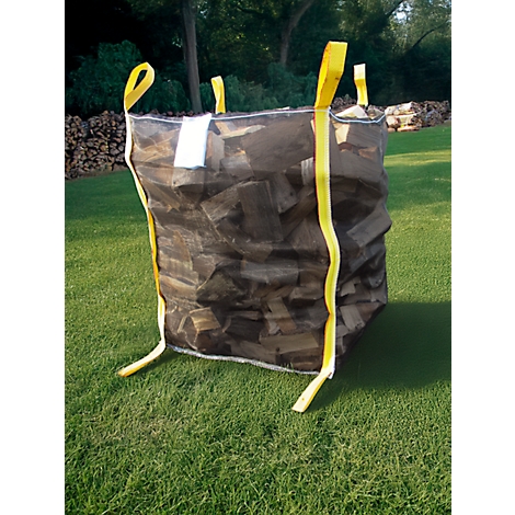Un grand sac rempli de bois de chauffage est posé sur une pelouse verte. Des sangles jaunes sont fixées aux coins.