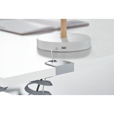 Close-up: Een zilveren klem die een USB-connector aan een wit tafelblad bevestigt.