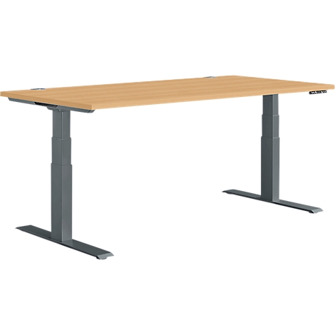 A height-adjustable desk with a light brown tabletop and grey metal legs.