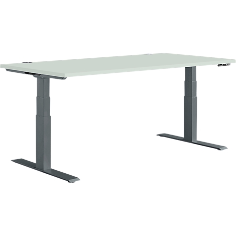 A white, height-adjustable desk with gray legs. The table frame and top form a rectangle, which can be adjusted in height.