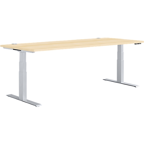 An adjustable height desk with a light brown table top and silver legs against a white background.