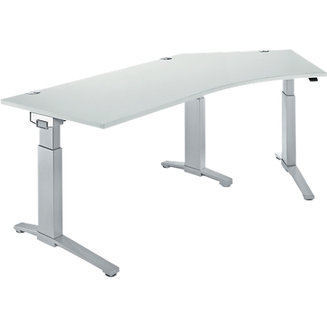 A white, ergonomic desk with silver, height-adjustable legs. Two openings for cables on the tabletop.