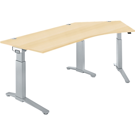 A height-adjustable desk with a light brown tabletop and silver legs, standing in a studio against a white background.